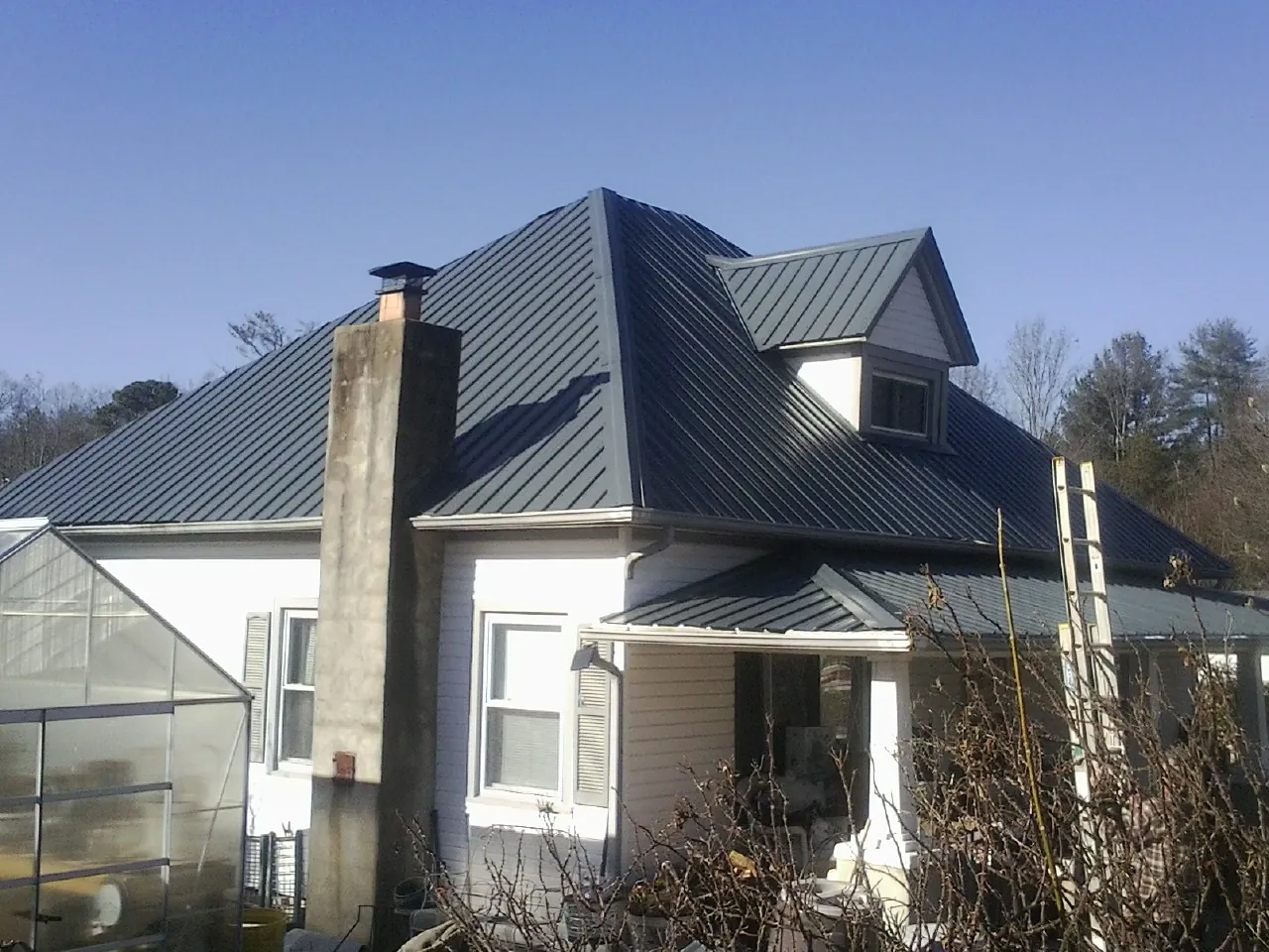 Dark blue standing seam metal roof on a white farmhouse with dormer — Slate & Tile Roof Repair by Roofing Brothers in North Plains