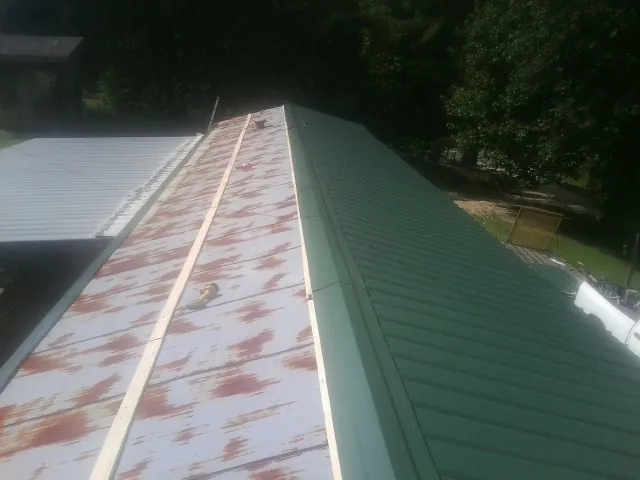 Old rusted panels beside newly installed green metal roofing — Wind Damage Roof Repair by Roofing Brothers in North Plains