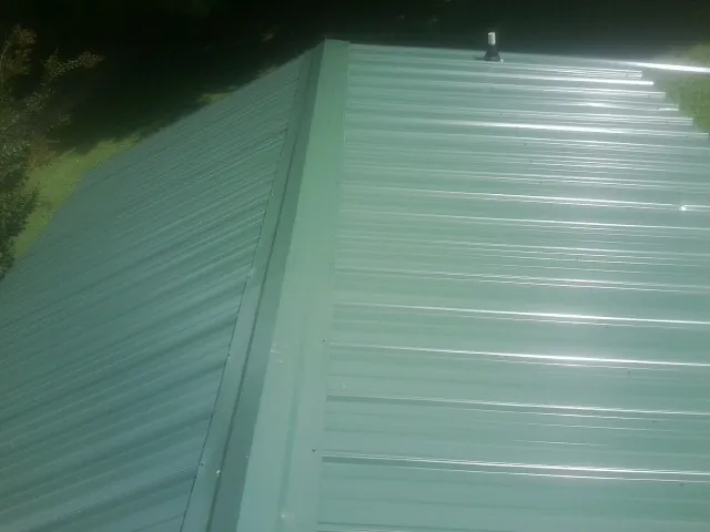 New green metal panels meeting at the ridge of a roof — Flat Roof Repair work by our crew in North Plains