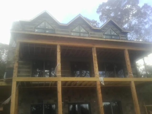 Dormers and porch framing on a large log home under construction — Roof Coating work by our crew in North Plains
