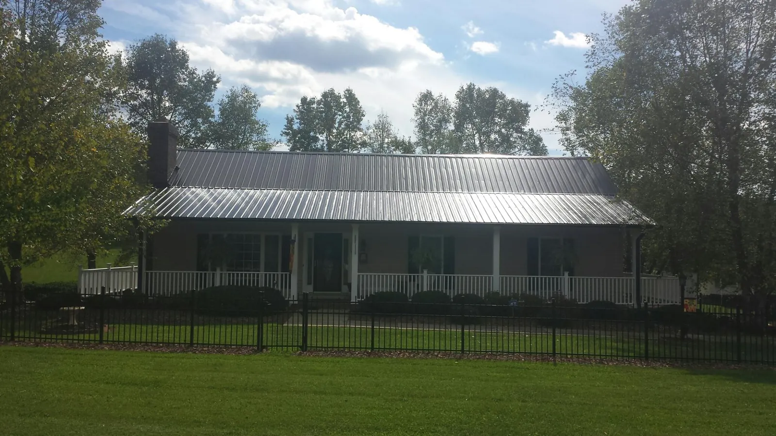 Gray metal roof on a brick ranch with a full width front porch — Gutter Guard Installation work by our crew in North Plains