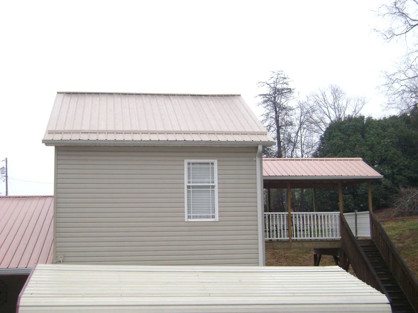 Tan metal roofs on a two story addition and attached porch, from a Roof Replacement job in North Plains