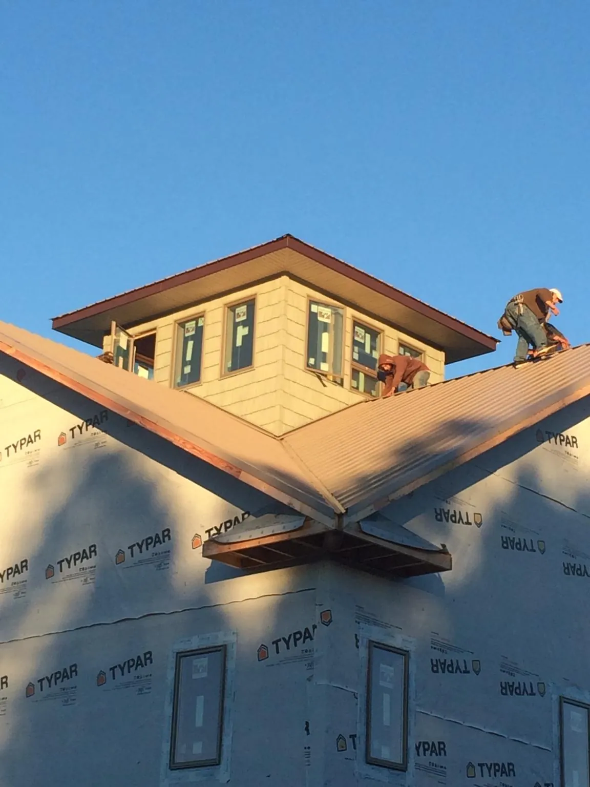 Roofers working around a rooftop cupola on a new metal roof at sunset — Roof Waterproofing in North Plains by Roofing Brothers